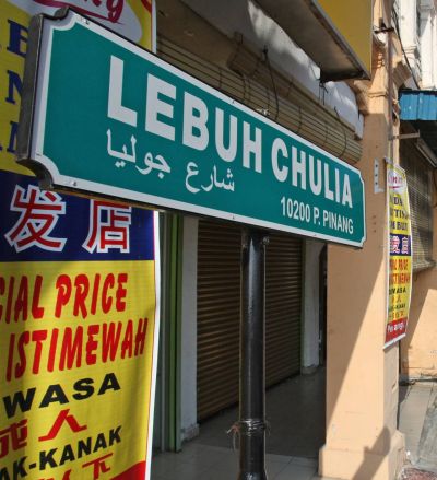 <b>Bilingual:</b> A road sign with Chulia Street’s name written in Bahasa Malaysia and Arabic.” width=”400″ height=”439″ /> <span class=